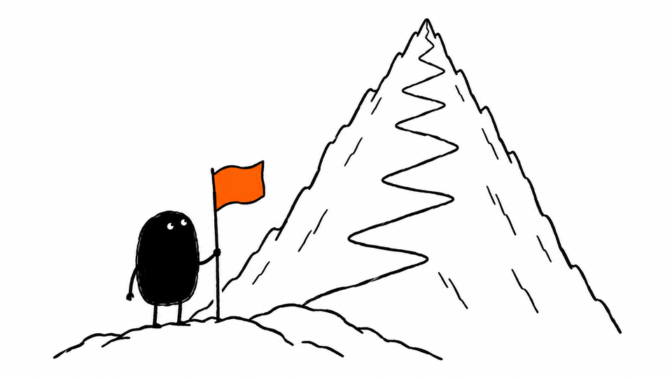 Lev stands at the foot of a mountain holding a small orange flag, looking up at the summit.
