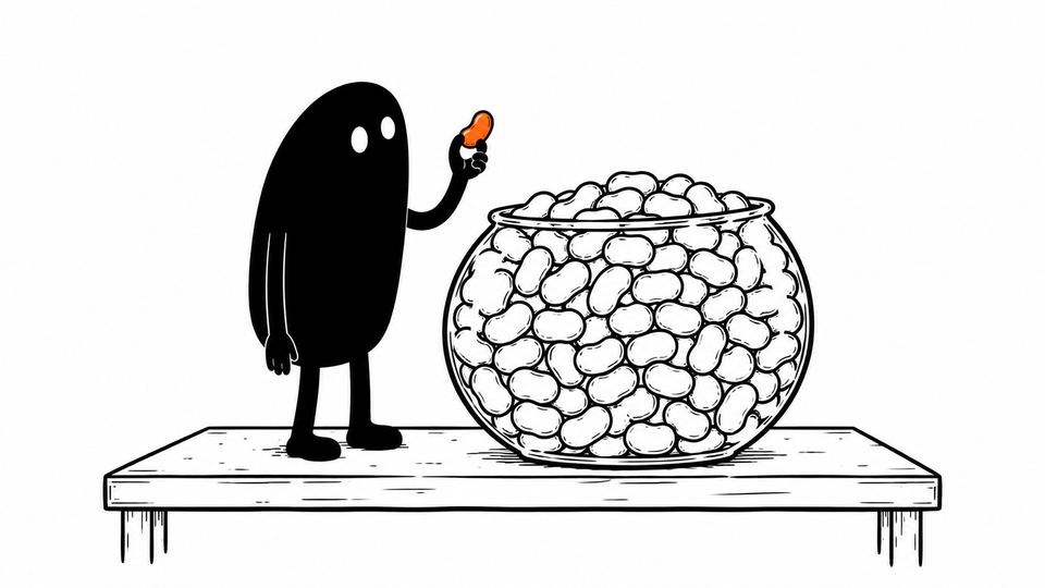 Lev holds up a single orange jellybean beside a huge bowl full of them.
