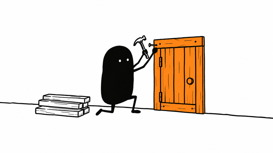 Lev hammers in the last nail of a small orange door he has built into a wall that had none.