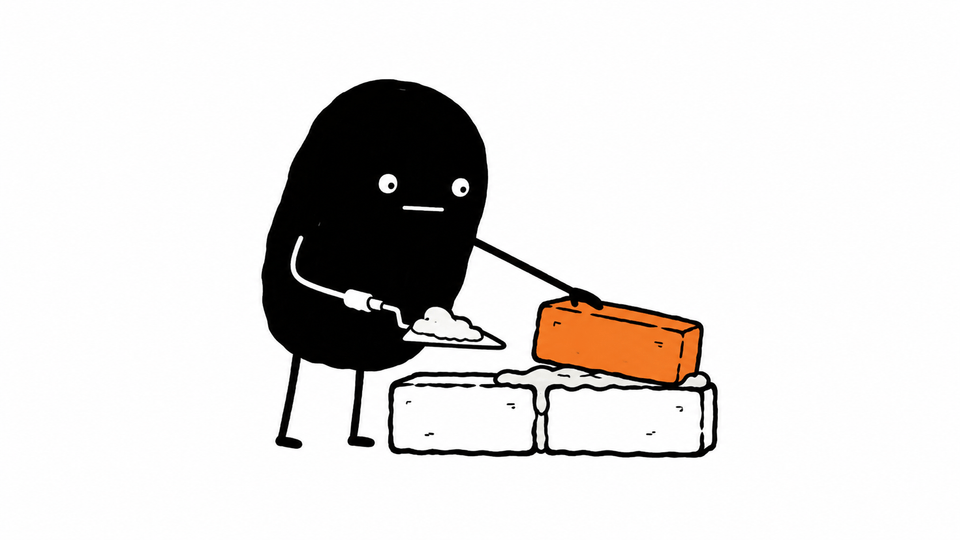 Lev lays the third, orange brick of a small wall with a trowel.