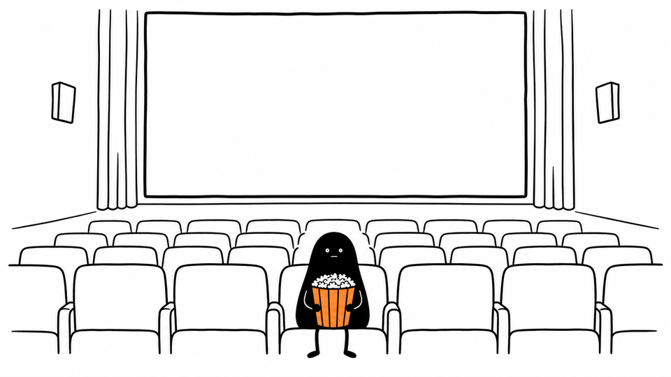 Lev sits alone in the front row of an empty cinema with an orange tub of popcorn, the screen still blank.